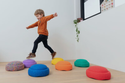Kleine jongen balanceert op gekleurde pads